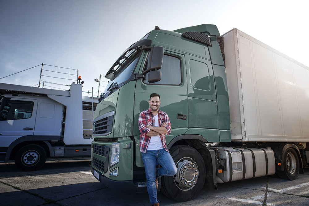 Truck driver with crossed arms and smile on his face standing by